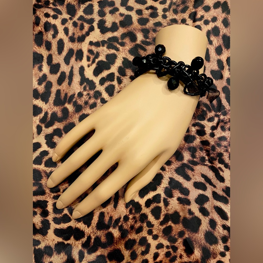 Creative black bracelet of beads, chains and ribbons.